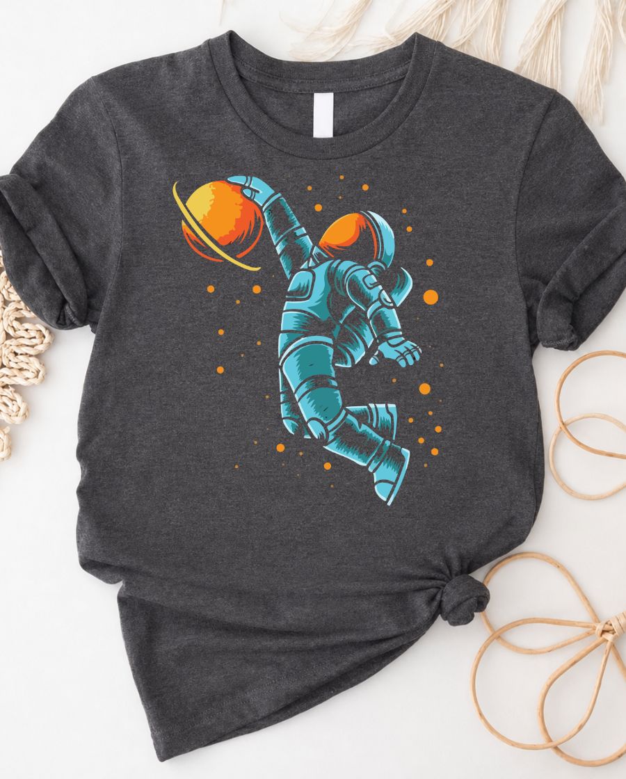 Astronaut playing basketball on moon surface graphic tee