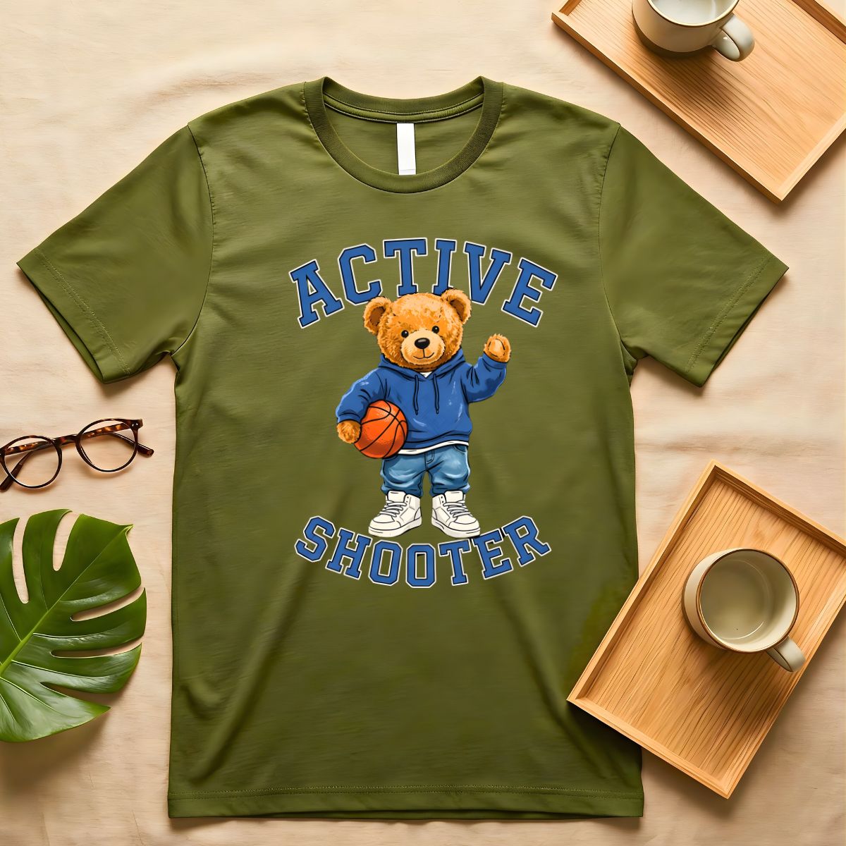 A person wearing a soft gray t-shirt with a vintage-style graphic of a bear wearing a sports headband, against a neutral background.