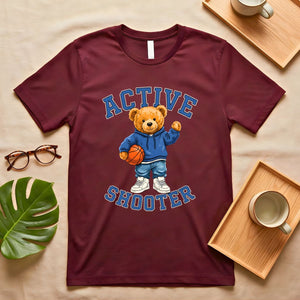 A person wearing a soft gray t-shirt with a vintage-style graphic of a bear wearing a sports headband, against a neutral background.