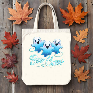 Tote bag with ghost design and 'Boo Crew' text on a wooden surface with autumn leaves