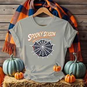 Funny Halloween T-shirt with “Spooky Season” print – black unisex jersey shirt flat lay with pumpkins and fall leaves
