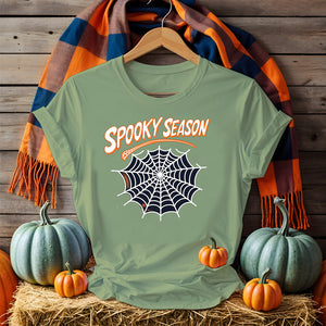 Funny Halloween T-shirt with “Spooky Season” print – black unisex jersey shirt flat lay with pumpkins and fall leaves
