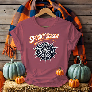 Funny Halloween T-shirt with “Spooky Season” print – black unisex jersey shirt flat lay with pumpkins and fall leaves