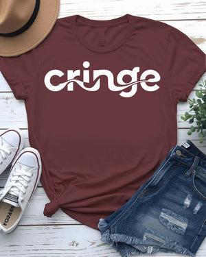 Model wearing the “Cringe” typographical t-shirt in black, smiling awkwardly, styled with denim and sneakers against a neutral background