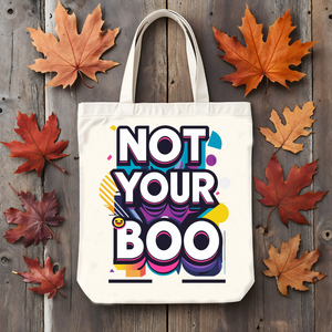 Tote bag with 'Not Your Boo' design on a wooden surface with autumn leaves