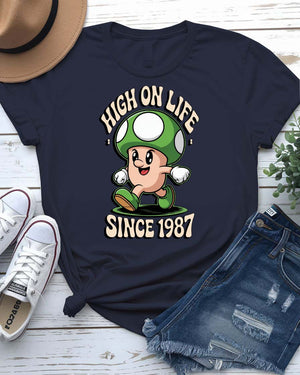 Retro meme T-shirt with High on Life Since 1987 text in vintage-style lettering, worn by a smiling model in natural light.