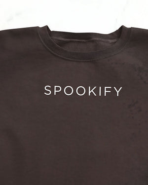 Spookify Halloween embroidered sweatshirt flat lay with pumpkin props.