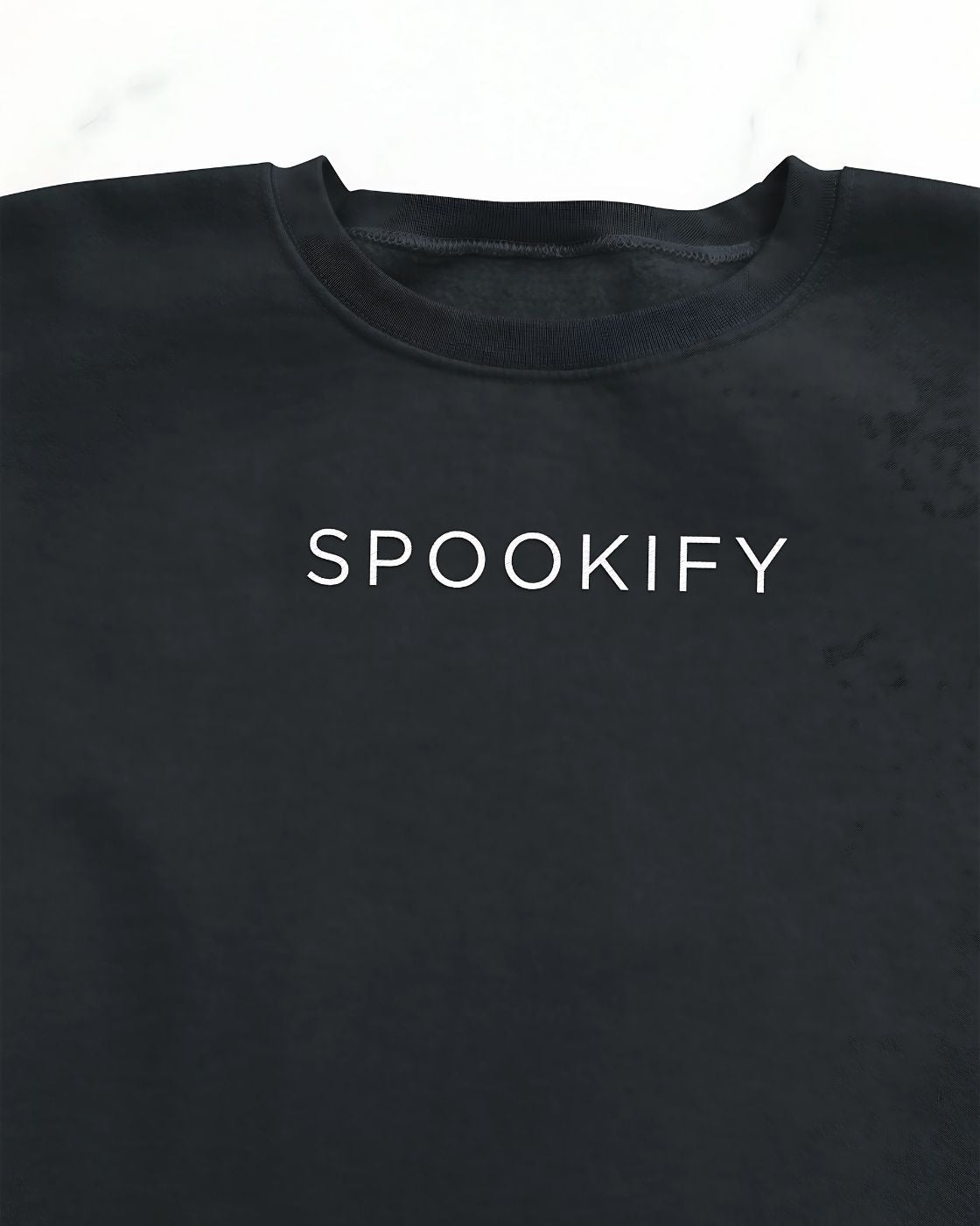 Spookify Halloween embroidered sweatshirt flat lay with pumpkin props.