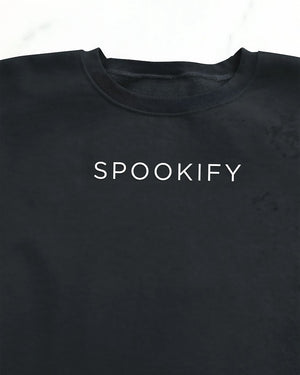 Spookify Halloween embroidered sweatshirt flat lay with pumpkin props.