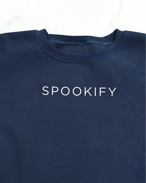 Spookify Halloween embroidered sweatshirt flat lay with pumpkin props.