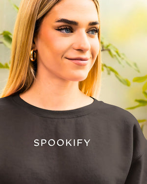 Spookify Halloween embroidered sweatshirt flat lay with pumpkin props.