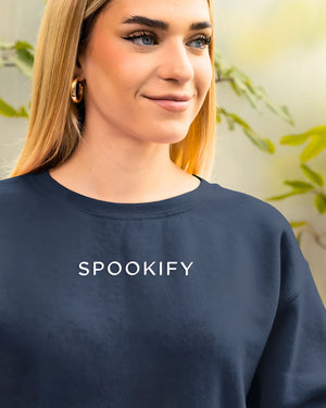 Spookify Halloween embroidered sweatshirt flat lay with pumpkin props.
