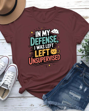 Unisex T-shirt with “In My Defense I Was Left Unsupervised” text in bold white distressed typography – worn by male and female models, casual setting.