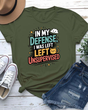 Unisex T-shirt with “In My Defense I Was Left Unsupervised” text in bold white distressed typography – worn by male and female models, casual setting.