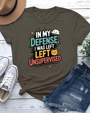 Unisex T-shirt with “In My Defense I Was Left Unsupervised” text in bold white distressed typography – worn by male and female models, casual setting.