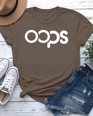 Unisex model wearing a white “Oops” typographical meme tee, styled casually with jeans, laughing and looking off-camera