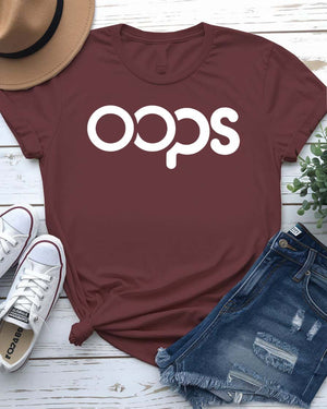 Unisex model wearing a white “Oops” typographical meme tee, styled casually with jeans, laughing and looking off-camera
