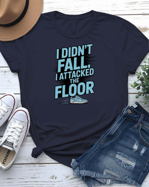 Unisex t-shirt featuring the text “I Didn’t Fall, I Attacked the Floor” in bold, modern typography — perfect for clumsy humor lovers.