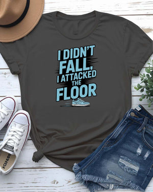 Unisex t-shirt featuring the text “I Didn’t Fall, I Attacked the Floor” in bold, modern typography — perfect for clumsy humor lovers.