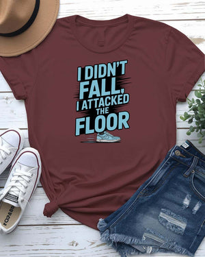 Unisex t-shirt featuring the text “I Didn’t Fall, I Attacked the Floor” in bold, modern typography — perfect for clumsy humor lovers.