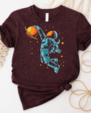 Astronaut playing basketball on moon surface graphic tee