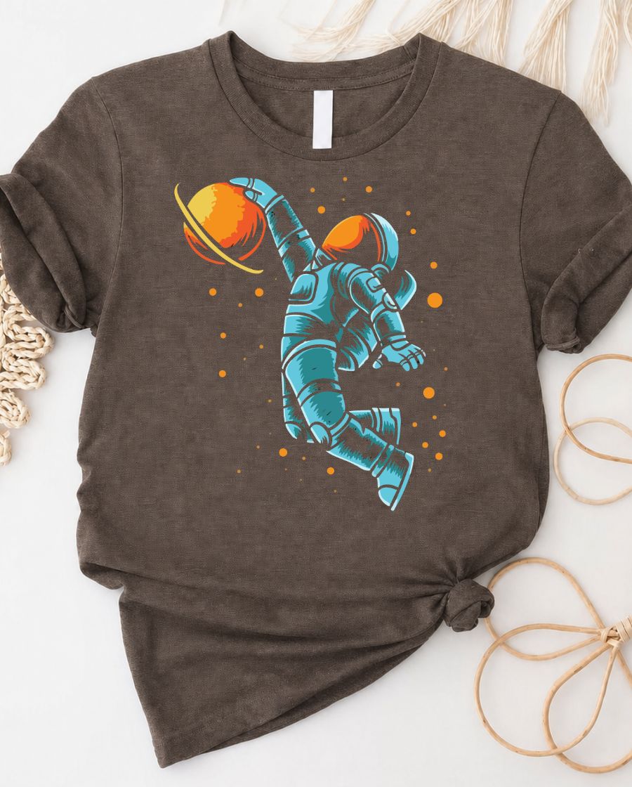Astronaut playing basketball on moon surface graphic tee