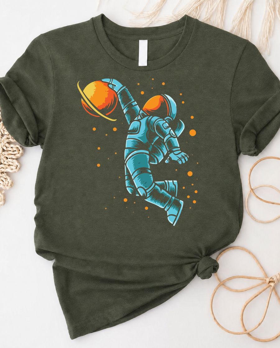 Astronaut playing basketball on moon surface graphic tee