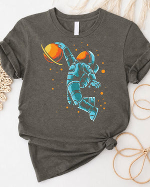 Astronaut playing basketball on moon surface graphic tee