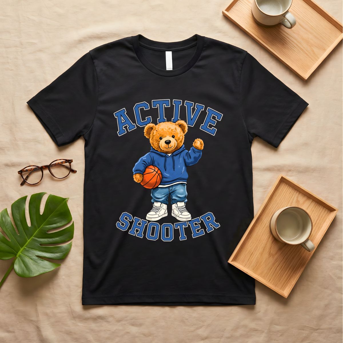 A person wearing a soft gray t-shirt with a vintage-style graphic of a bear wearing a sports headband, against a neutral background.