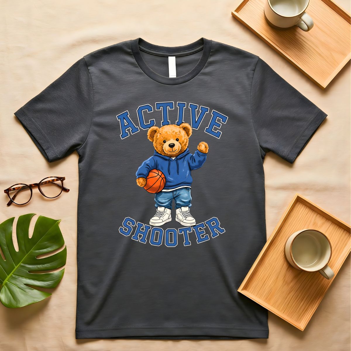 A person wearing a soft gray t-shirt with a vintage-style graphic of a bear wearing a sports headband, against a neutral background.