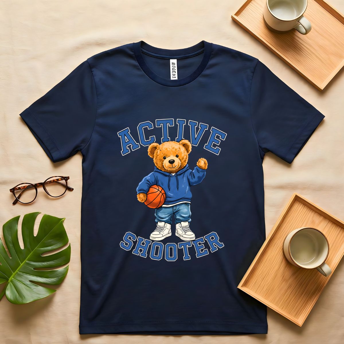 A person wearing a soft gray t-shirt with a vintage-style graphic of a bear wearing a sports headband, against a neutral background.