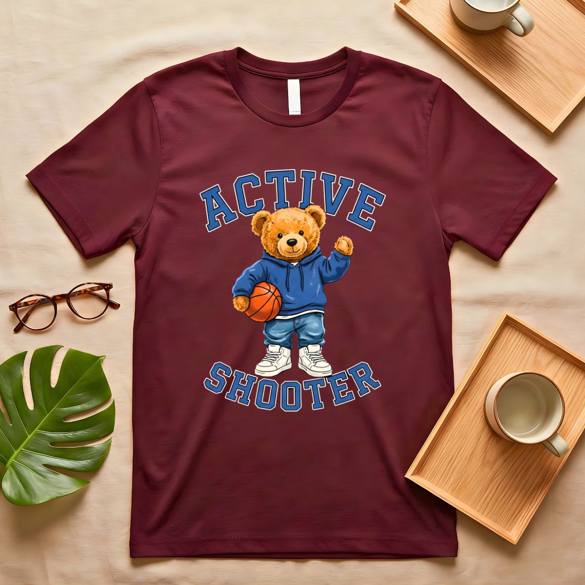 A person wearing a soft gray t-shirt with a vintage-style graphic of a bear wearing a sports headband, against a neutral background.
