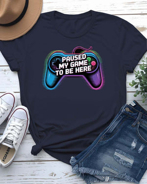Unisex tee with bold “Paused My Game to Be Here” text in pixel-style typography, modeled by gamer in headset and controller.