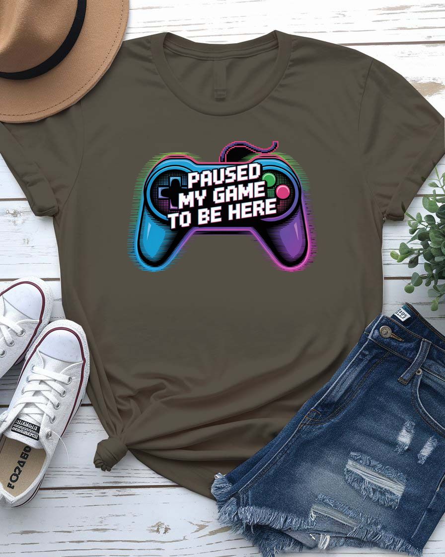 Unisex tee with bold “Paused My Game to Be Here” text in pixel-style typography, modeled by gamer in headset and controller.